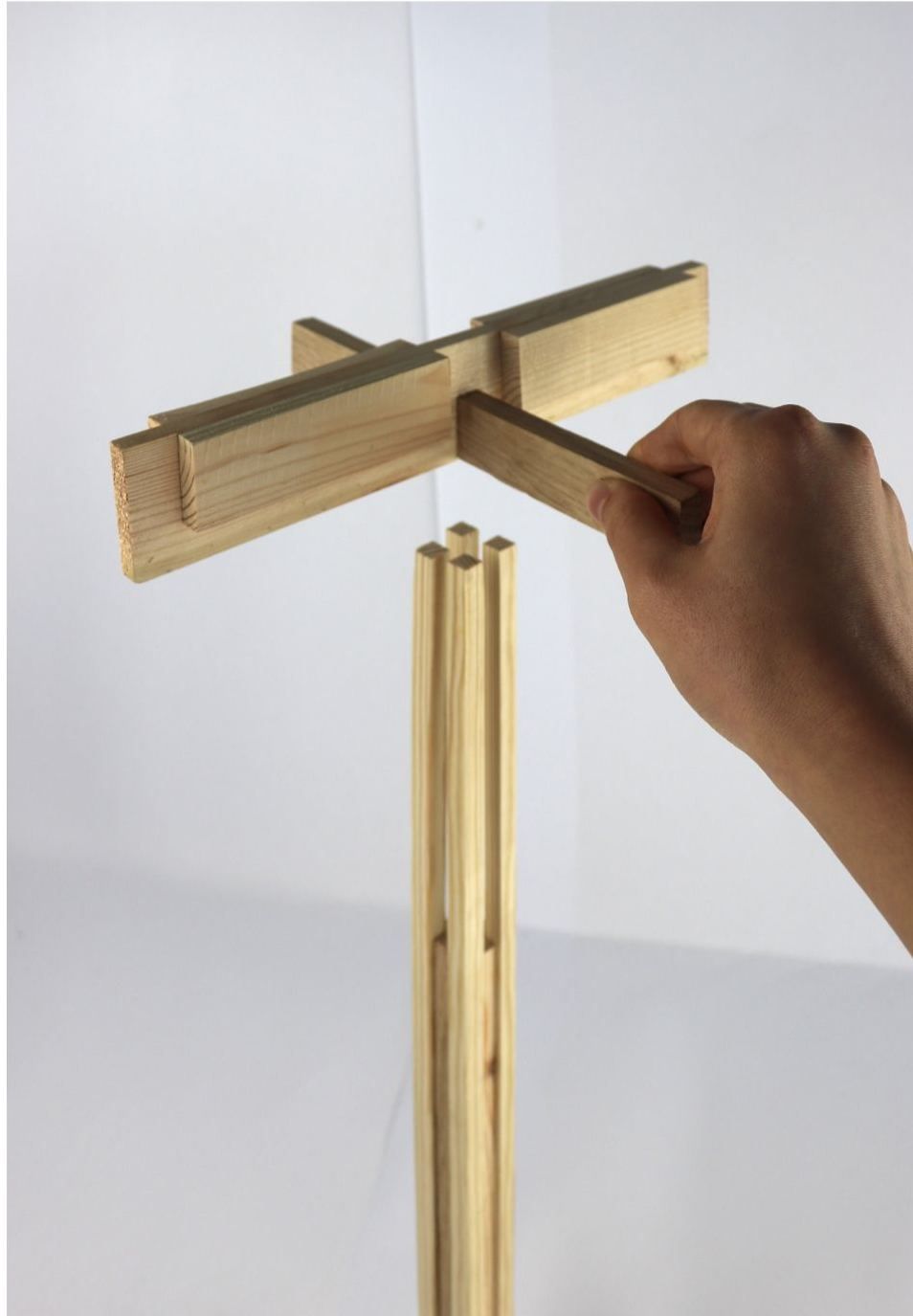 A hand fitting together a model of a timber column built from smaller pieces